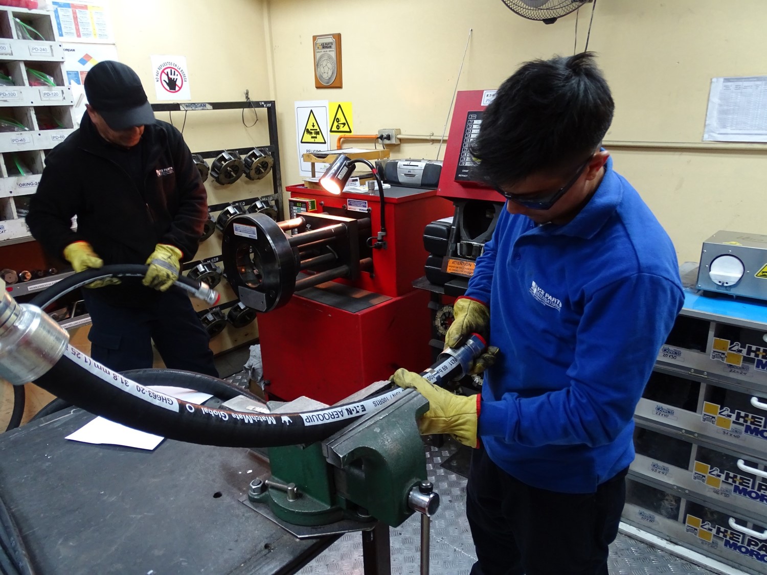 H-E Parts employee attaching hose fitting to aeroquip hose